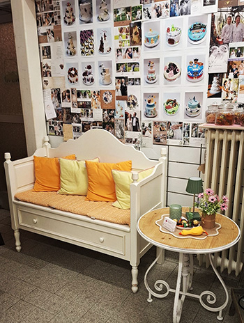 Ein gemuetliches Sofa steht vor einer Wand mit Fotos von Tortenfotos